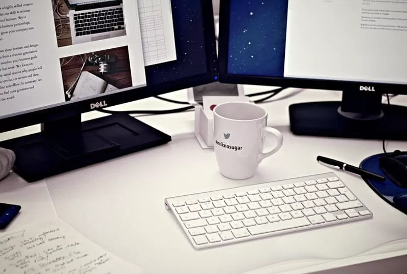 Coffee mug and two computer screens